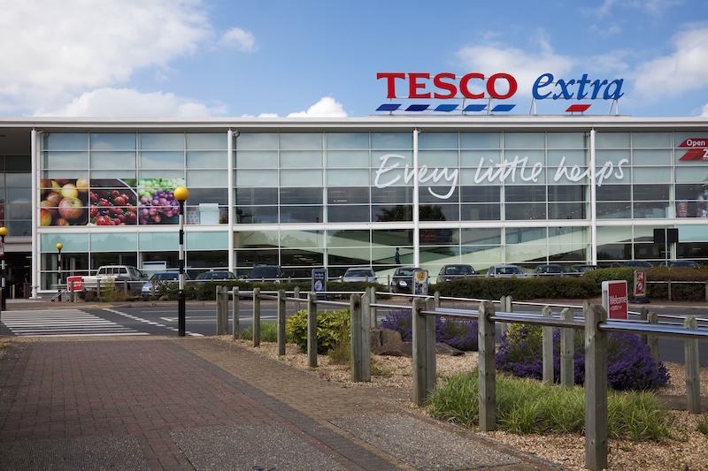 "Altrincham, UK - July 7, 2012: Tesco Supermarket sign, logo and slogan on the store in Altrincham, Cheshire, UK. Tesco is a multinational retailer of groceries and general goods, and is based in the UK. They are the second-largest retailer in the world measured by profits. Tesco Extra stores are larger hypermarkets selling a wide range of goods."